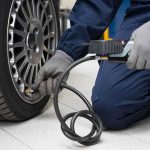 Mechanic inflating a car tire in a workshop