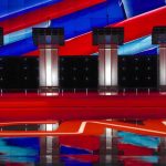 Debate Clip Haunts A-List Streamer Debate stage with four empty podiums and bright red and blue backdrop