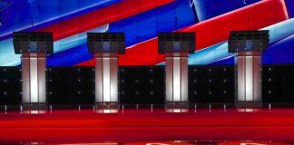 Debate Clip Haunts A-List Streamer Debate stage with four empty podiums and bright red and blue backdrop