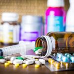 Medicine pills and syringe on table with brown bottle