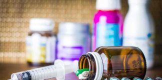 Gas-Station Gummies Treated Like Heroin Medicine pills and syringe on table with brown bottle