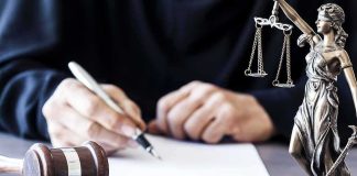 Postpartum Psychosis Or Premeditation? Judge writing at desk with gavel and Lady Justice statue