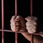 She Fought Back — They Hanged Her Hands gripping prison bars