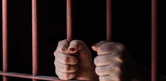 Hands gripping prison bars