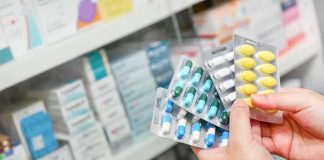 Hands holding blister packs of assorted pills in a pharmacy