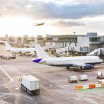 Bloody Cockpit Brawl at 35,000 Feet Airplanes at airport gates during sunset with ground vehicles and jet bridges