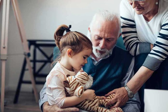 Little girl holding a stuffed tiger with two older adults nearby