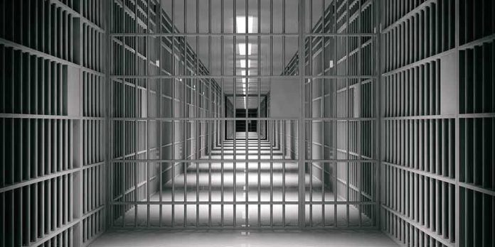 shutterstock_1118920109 empty prison corridor with barred cells
