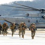 Cyber Recruits Score Surprise Cash Soldiers disembark and walk past a large military helicopter