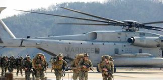 Cyber Recruits Score Surprise Cash Soldiers disembark and walk past a large military helicopter
