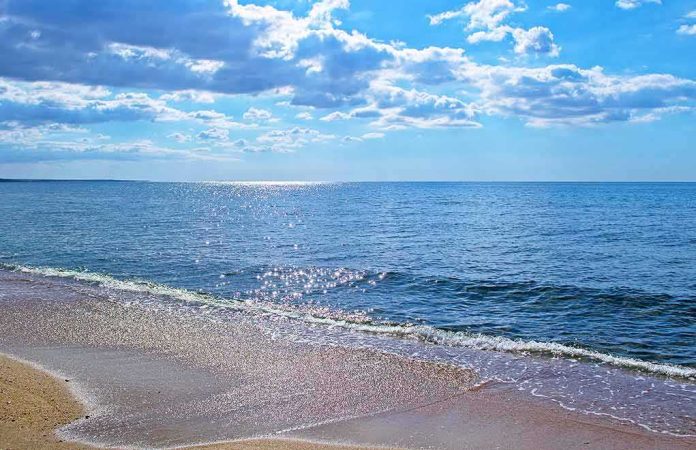 Sandy beach with gentle waves under a bright blue sky