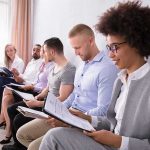 Group of job applicants sitting in a row reviewing documents