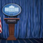 Trump’s New Military Spouse Panel White House press briefing podium with U.S. flag and blue curtain