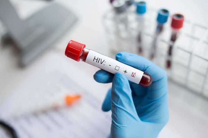 Gloved hand holding a blood sample tube labeled for HIV test