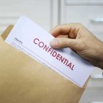 Rolling UFO Releases Raise Eyebrows Hand placing confidential document into a brown envelope