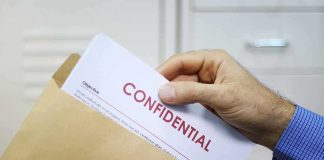 Rolling UFO Releases Raise Eyebrows Hand placing confidential document into a brown envelope