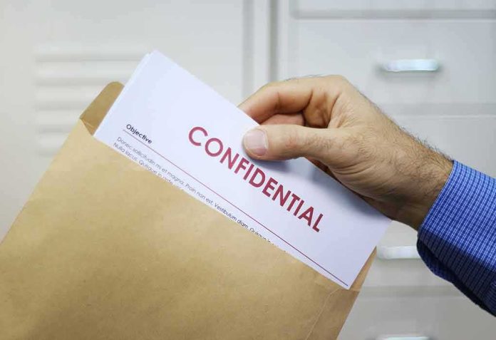 shutterstock_128095721 Hand placing confidential document into a brown envelope