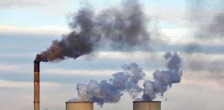 Industrial power plant with smokestack and cooling towers emitting smoke
