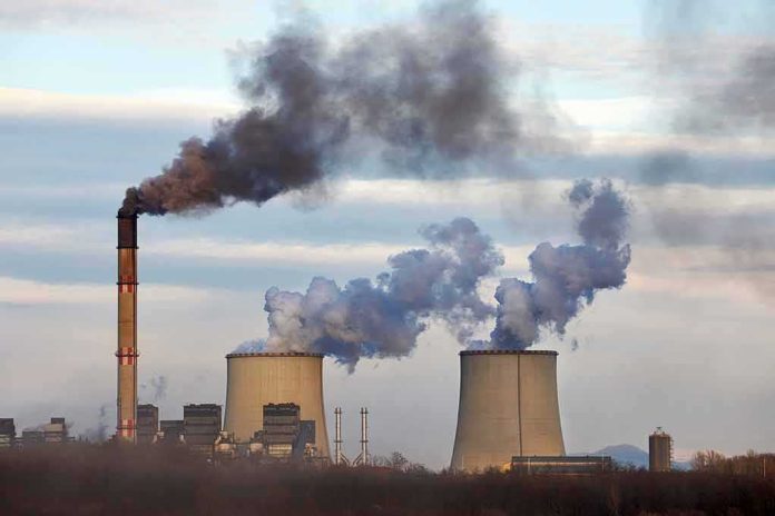 Industrial power plant with smokestack and cooling towers emitting smoke