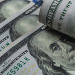 Bailout King Returns: Kevin Warsh’s Hidden Wealth U.S. 100-dollar bills with one note rolled over Benjamin Franklin portrait