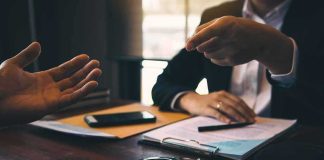 Two people in discussion at a desk with handcuffs and documents