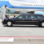 Presidential motorcade limousine parked beside large blue and white aircraft