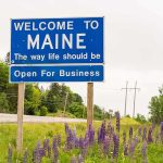 Welcome to Maine roadside sign with wildflowers
