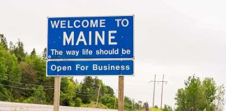 Property Seizure? Maine Bombshell Looms Welcome to Maine roadside sign with wildflowers