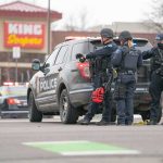 Shelter Orders Grip Texas City Police officers gather beside a patrol SUV at a taped-off scene
