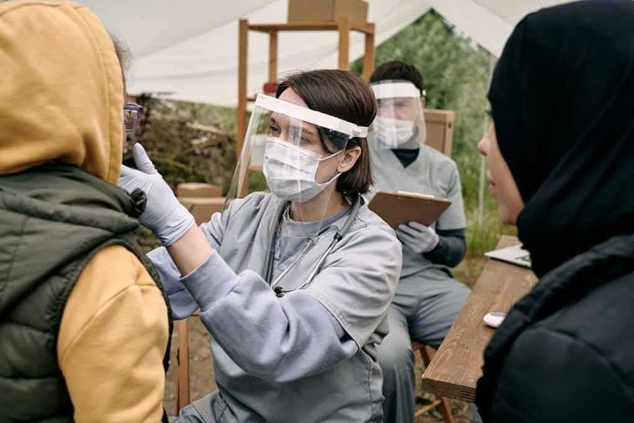 shutterstock_2042550827 Healthcare worker in PPE examines a patient at an outdoor clinic