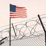 American flag above barbed wire fence