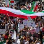 Currency Freefall Triggers Unrest Fears Crowd of protesters holding signs and a large tricolor flag