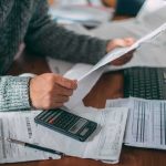 Free Speech Showdown: $5B on the Line Person reviewing bills with calculator at cluttered desk