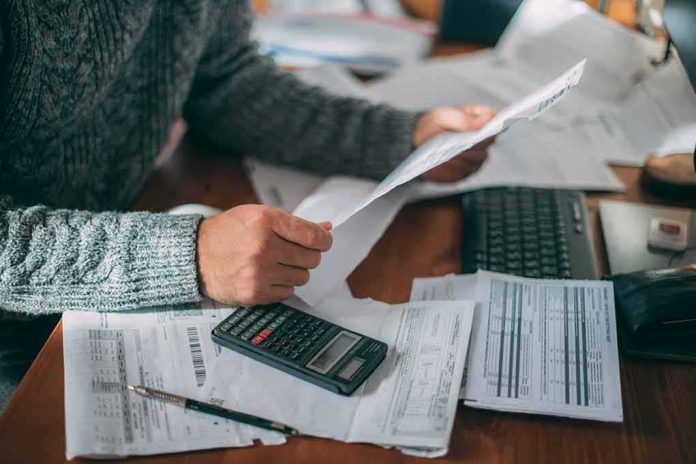 Person reviewing bills with calculator at cluttered desk