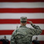 Non-Combat Death Officer Identified Soldier saluting before a large American flag