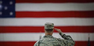 Soldier saluting before a large American flag