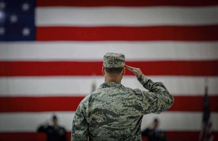 shutterstock_2589821743 Soldier saluting before a large American flag