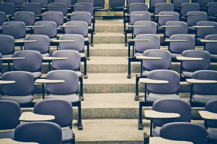 Empty lecture hall with rows of blue seats and foldable desks