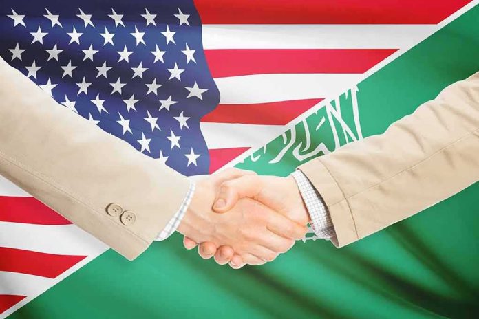 shutterstock_283346258 Handshake between two people over U.S. and Saudi flags