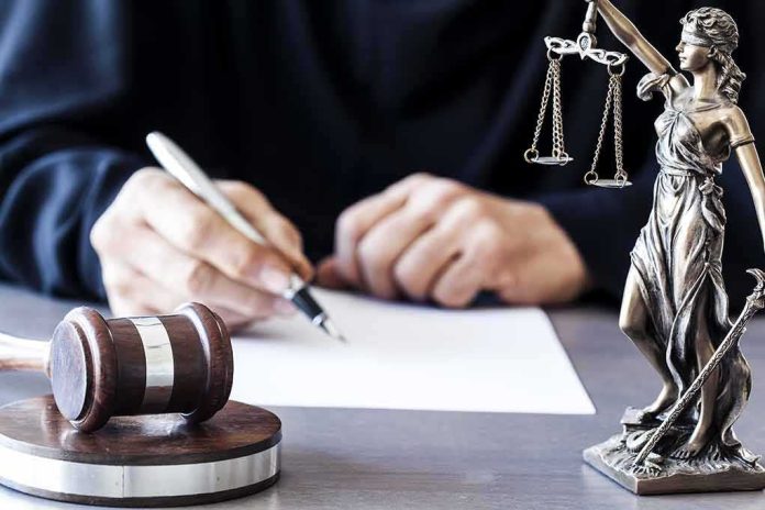 shutterstock_565403533-3 Judge writing at desk with gavel and Lady Justice statue
