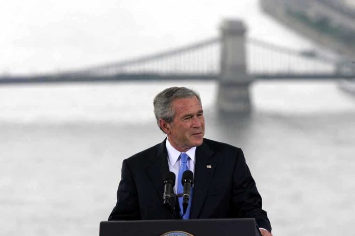 A man in a suit giving a speech at a podium with a bridge in the background