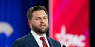 Final Push: Vance Packs Michigan Man in suit speaking at a podium with microphone