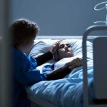 Ivermectin Hype Meets Cold Reality Patient in hospital bed with visitor holding their hand