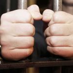 hands gripping prison bars