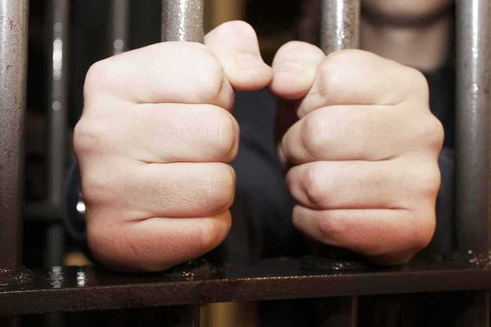 shutterstock_108342344 hands gripping prison bars