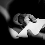 Hands exchanging a white envelope