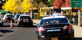 Gunman Downed By Furious Father Police cars with lights on near school buses on a city street