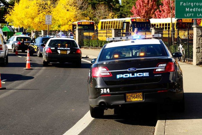 shutterstock_117302929-2-1-1 Police cars with lights on near school buses on a city street