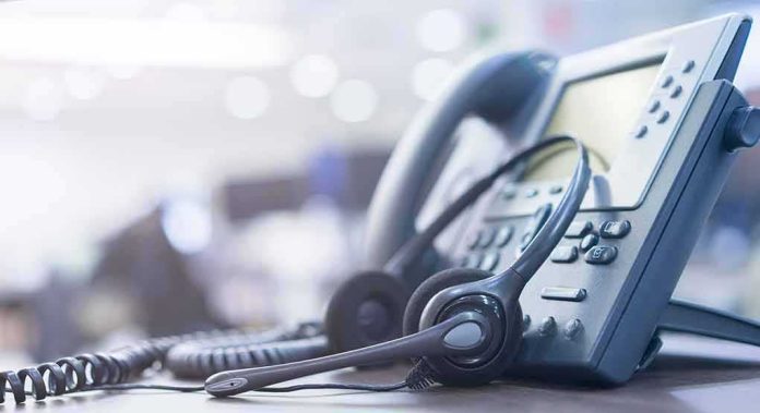 shutterstock_1248023887 Headset resting on an office desk phone