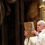 Catholic priest holds ornate book during ceremony
